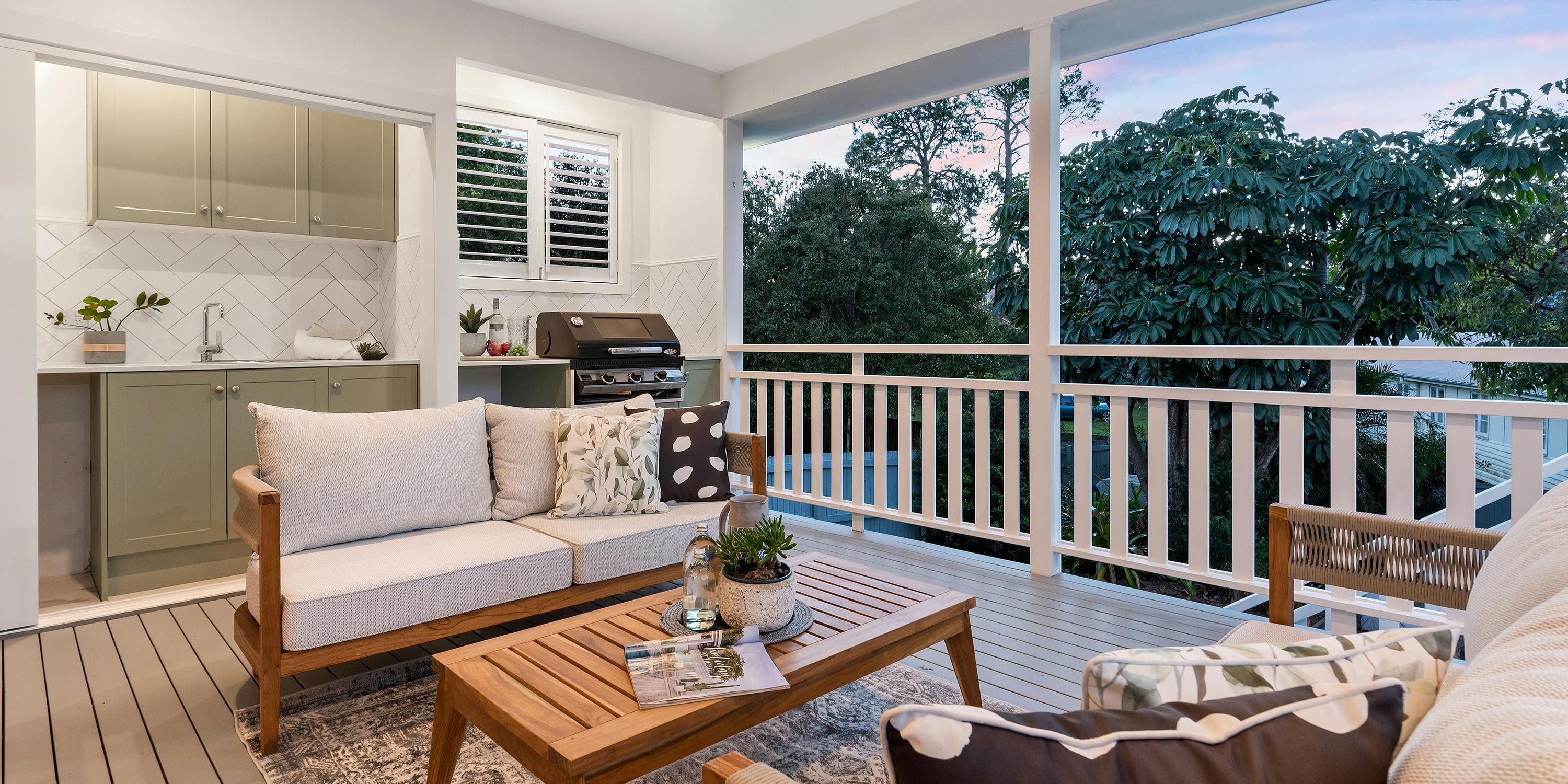 A stylish outdoor living area featuring a large TV, modern furniture, and a wooden deck, designed for relaxation and entertainment.