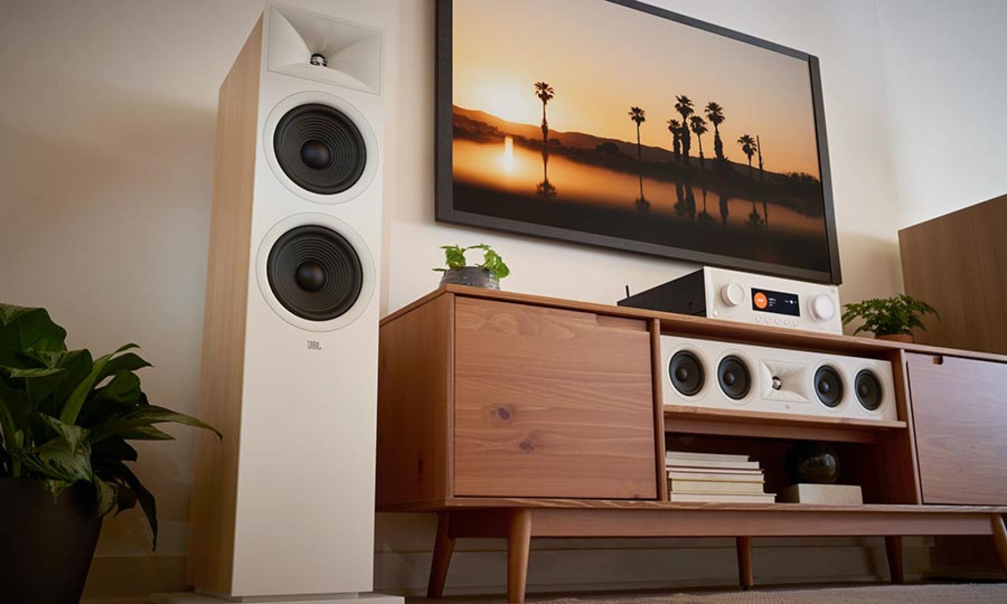 A stylish living room featuring a large tower speaker beside a media console, with a television displaying a sunset scene.